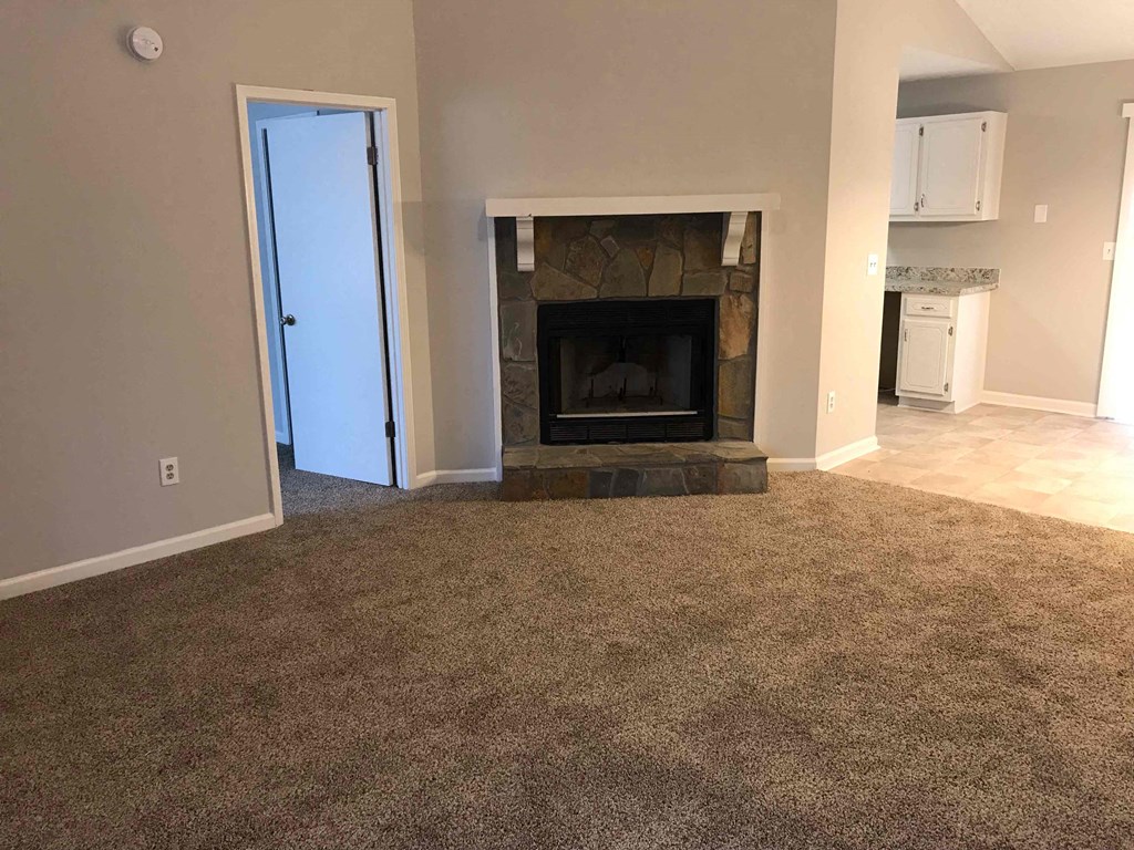A room with a fireplace and a carpeted floor.
