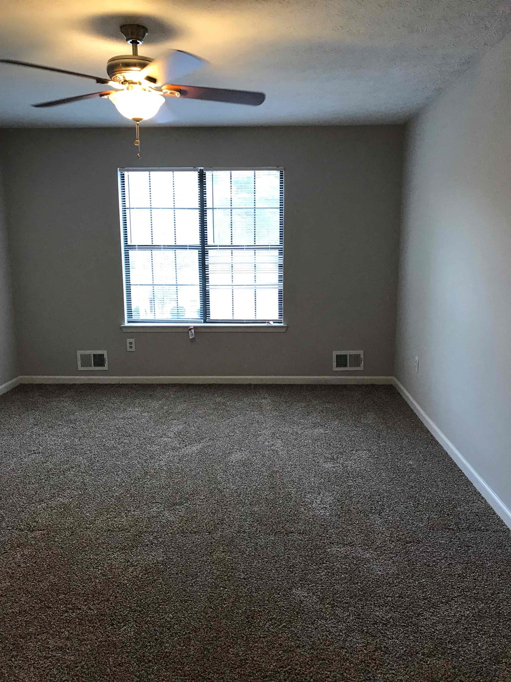 A room with a ceiling fan and a window.