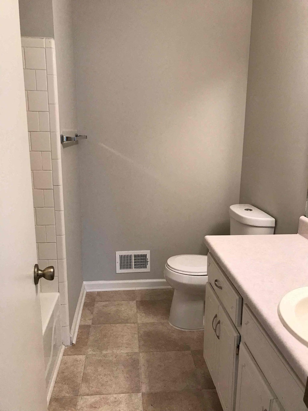 A white toilet sits in a bathroom next to a sink.