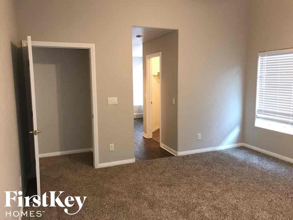 an empty room with a door open to a hallway and a door to a bedroom