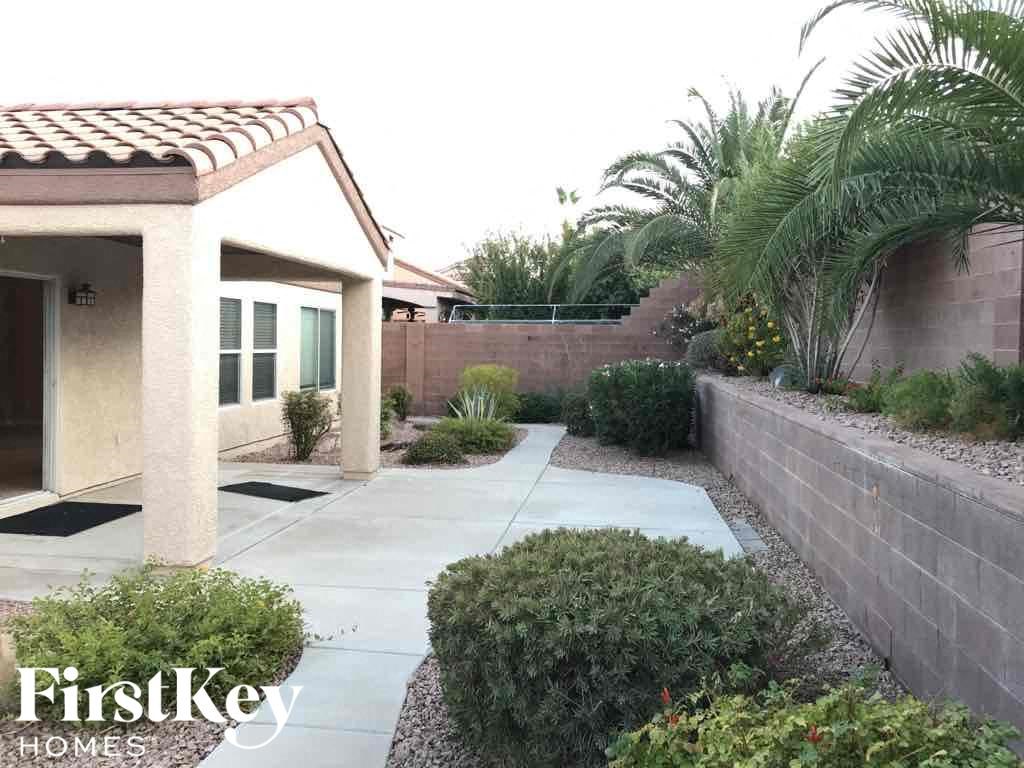 a sidewalk leading to a house with a fence and palm trees