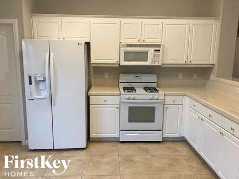 a kitchen with white cabinets and appliances and a refrigerator