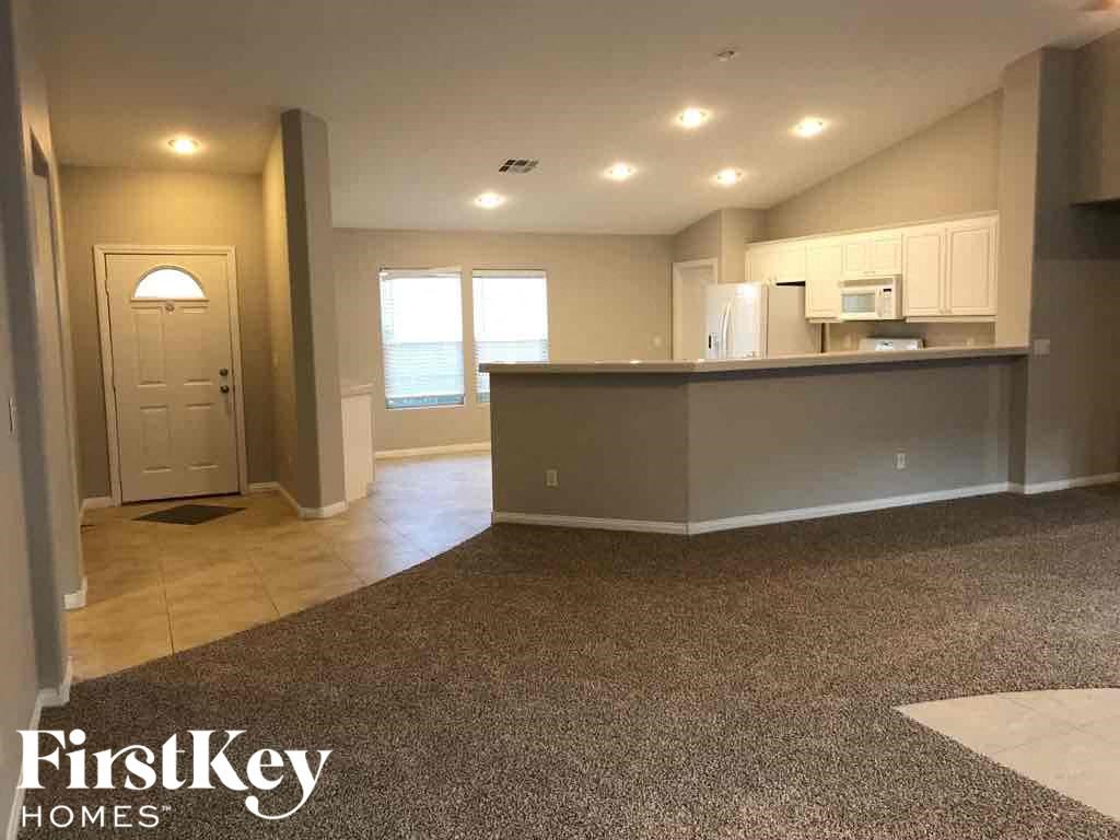 an empty living room with a kitchen and a counter top