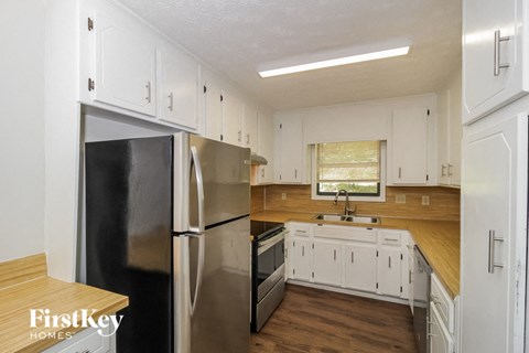 A kitchen with white cabinets and a black fridge.