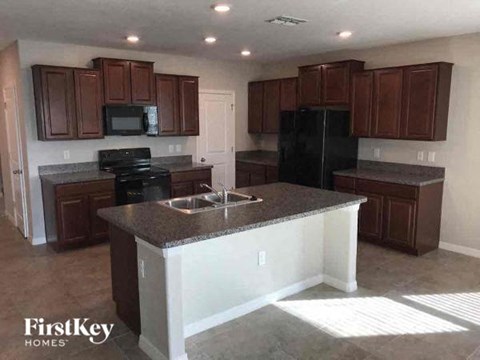 A kitchen with brown cabinets and a black refrigerator.
