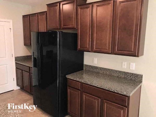 A black refrigerator is in a kitchen with brown cabinets.