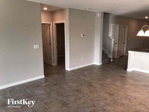 A room with a tile floor and a kitchen area in the background.