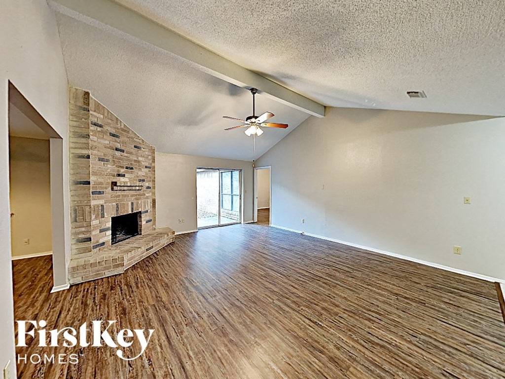 an empty living room with a fireplace and a ceiling fan