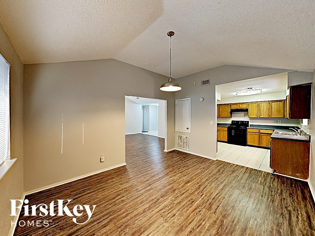 an empty living room and kitchen with wood flooring
