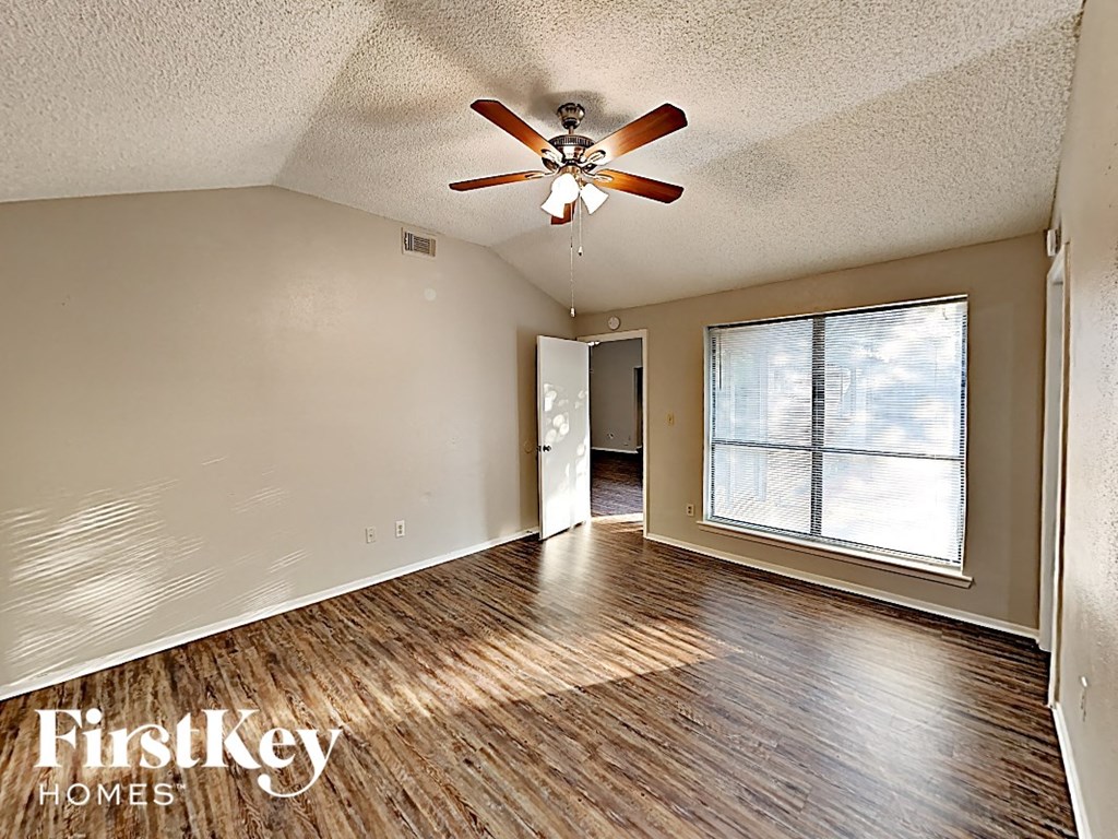 an empty living room with a ceiling fan and a large window