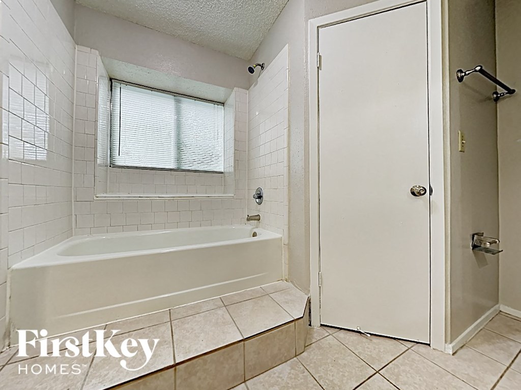 a white bathroom with a tub and a shower and a door