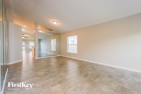 A spacious room with a tiled floor and a glass wall on the left side.