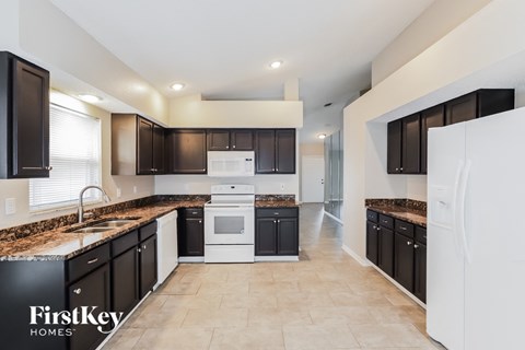 A kitchen with black cabinets and a white fridge.