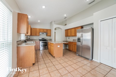 A kitchen with wooden cabinets and a tile floor.