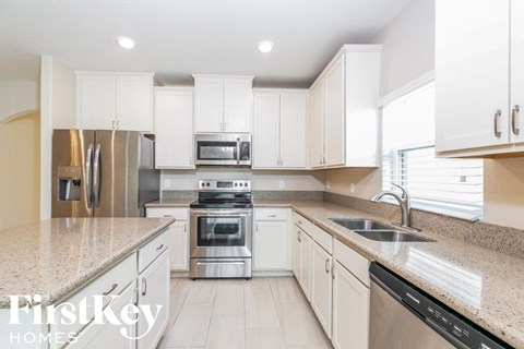 a white kitchen with granite counter tops and stainless steel appliances