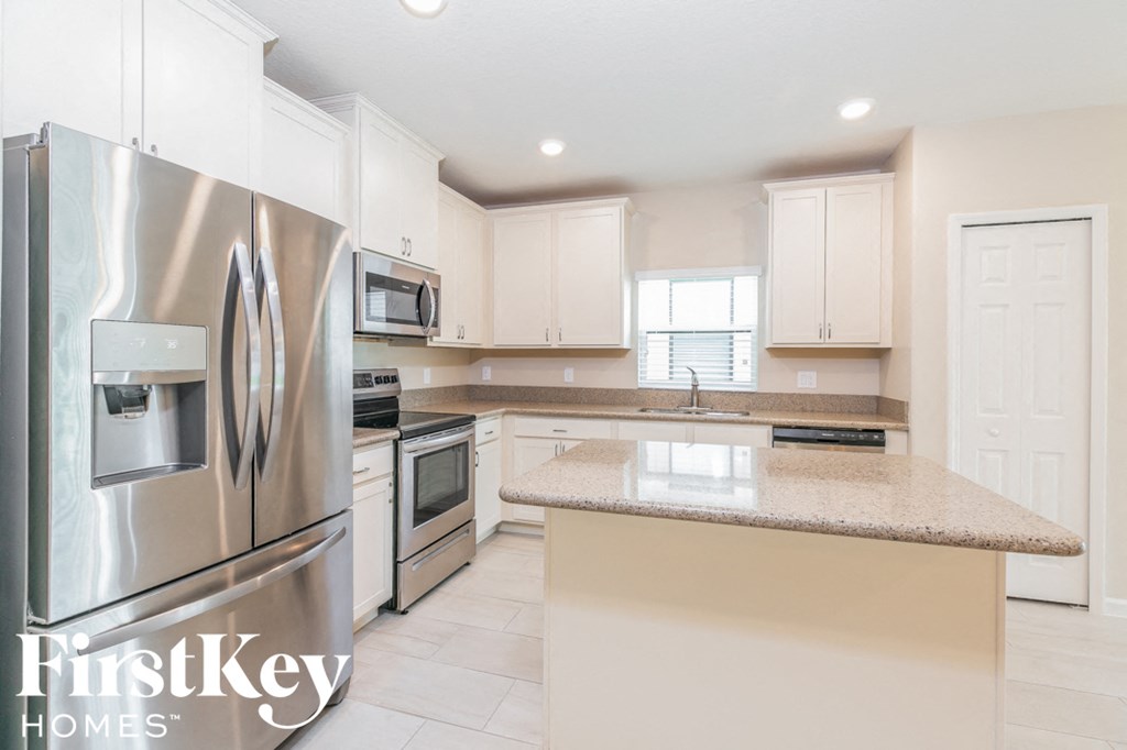 a white kitchen with stainless steel appliances and granite counter tops
