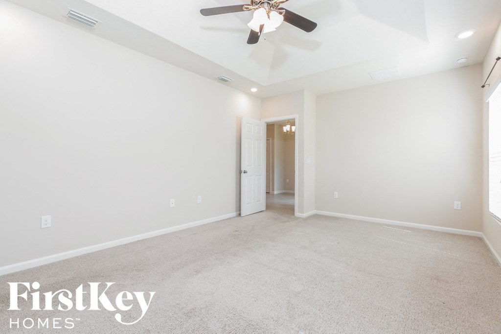 a empty living room with a ceiling fan and white walls