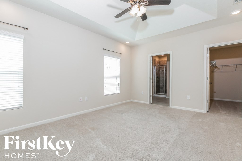 an empty living room with a ceiling fan and a closet