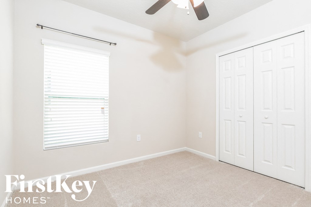 a bedroom with two closets and a window and a ceiling fan