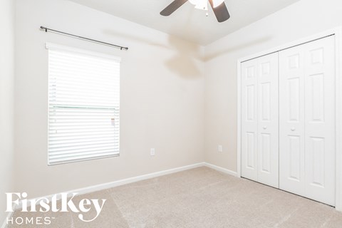 a bedroom with two closets and a window and a ceiling fan