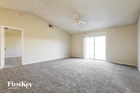 A spacious room with a carpeted floor and a ceiling fan.