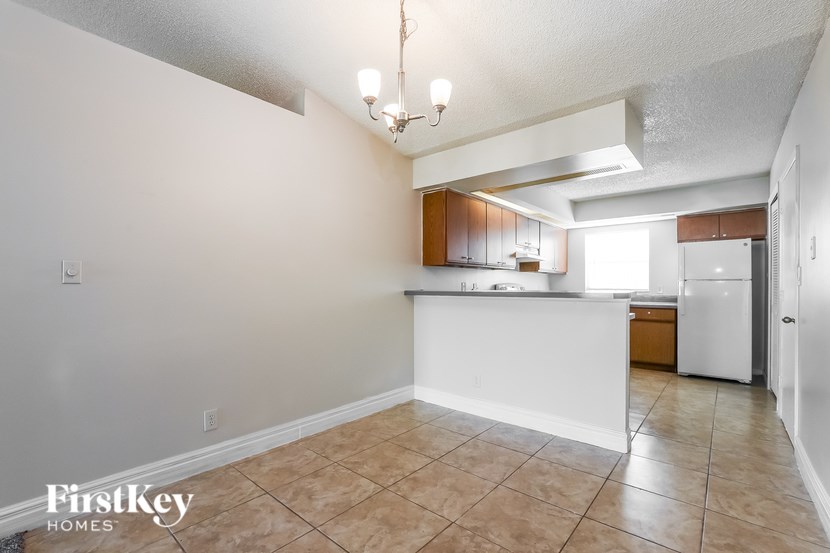A kitchen area with a refrigerator, cabinets, and a countertop.