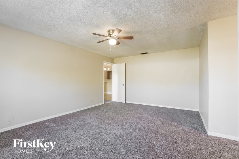 A spacious room with a ceiling fan and a door leading to another room.