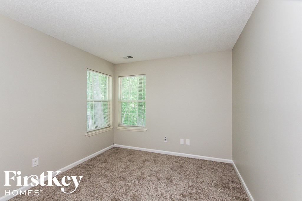 a bedroom with a carpeted floor and two windows