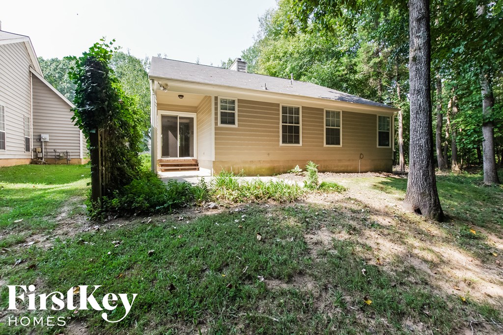 the front of a yellow house with a yard and trees