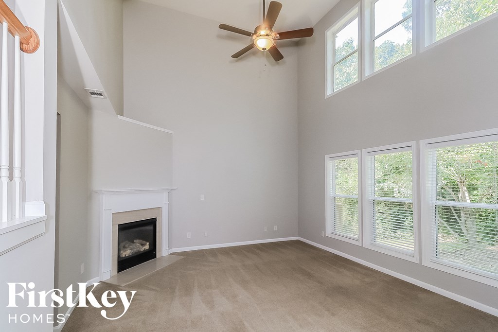 A spacious living room with a fireplace and a ceiling fan.