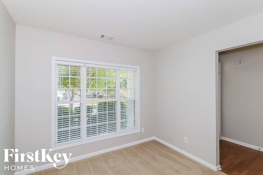A room with a window covered by white blinds.