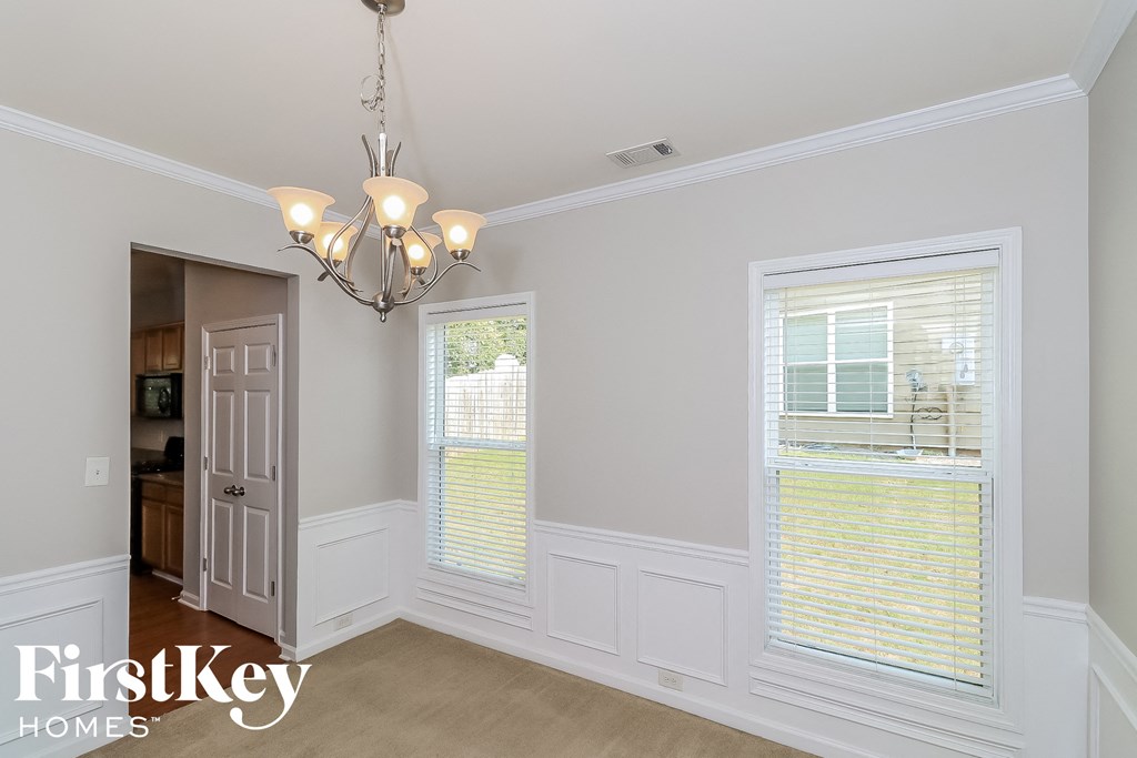 A well-lit room with a chandelier and a window with blinds.