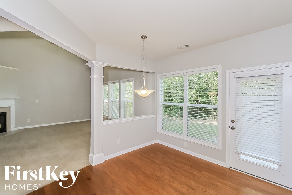 A room with a wooden floor and a large window with blinds.