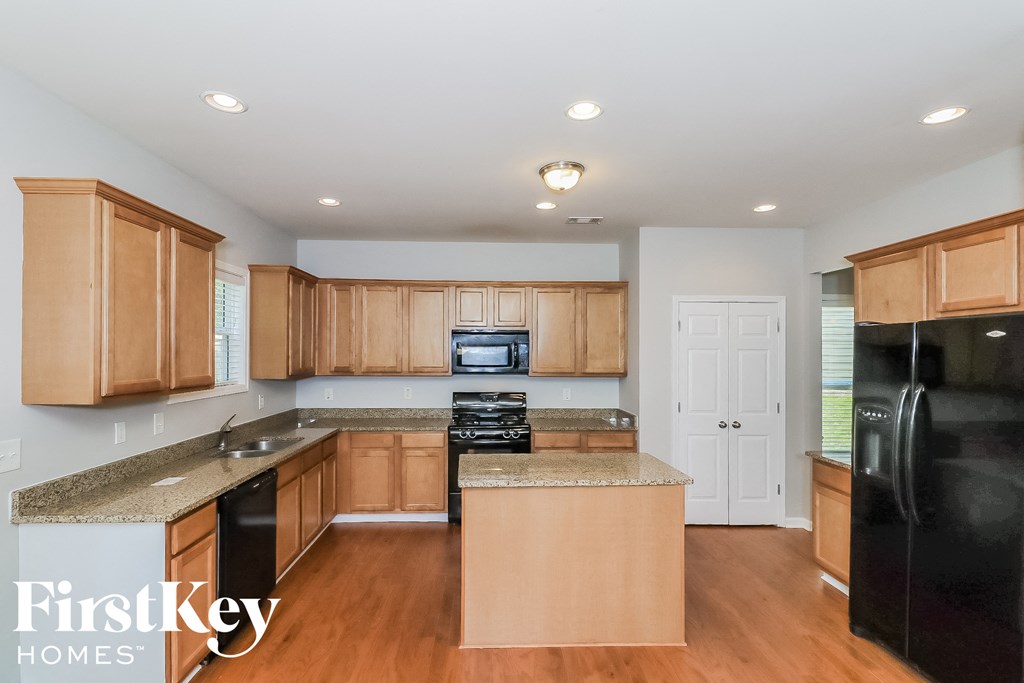 A kitchen with wooden cabinets and a black refrigerator.