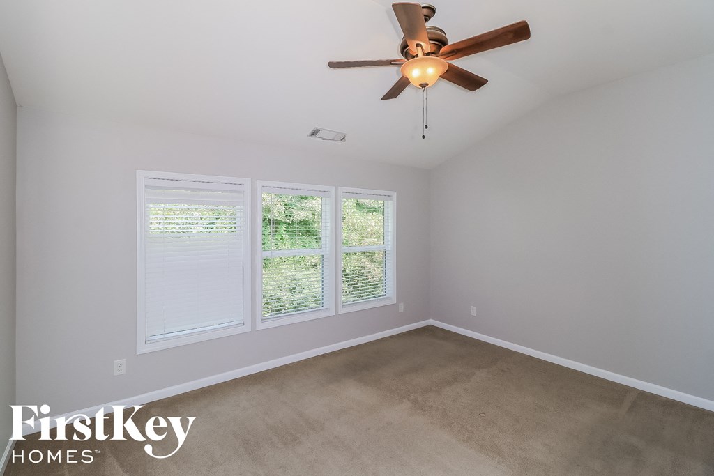 A room with a ceiling fan and a window with blinds.