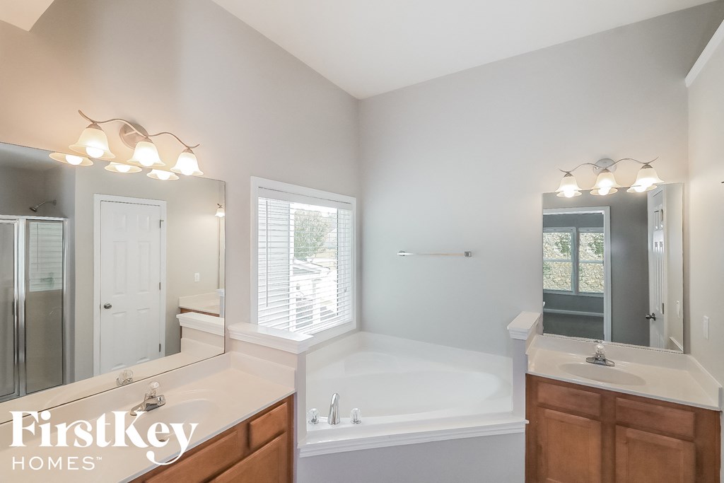 A well-lit bathroom with a large mirror and a bathtub.
