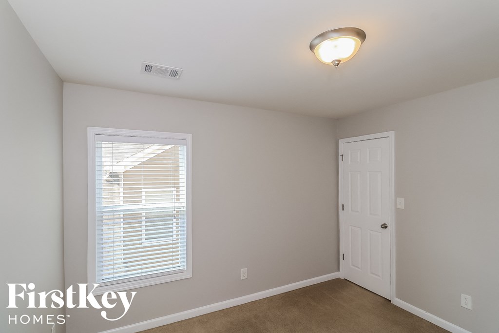 A room with a white door and a window with blinds.