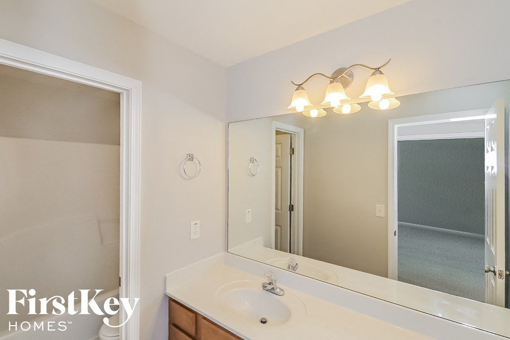 A bathroom with a sink, mirror and lights.