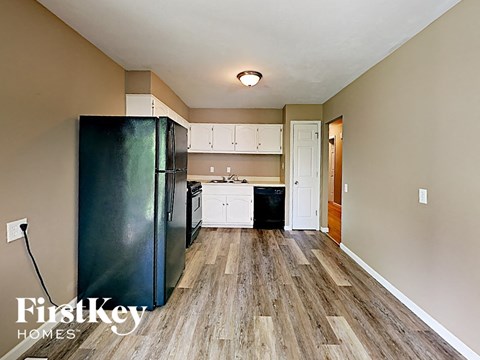 A kitchen with a black fridge and wooden floors.