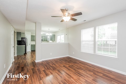 A spacious room with wooden floors and a ceiling fan.