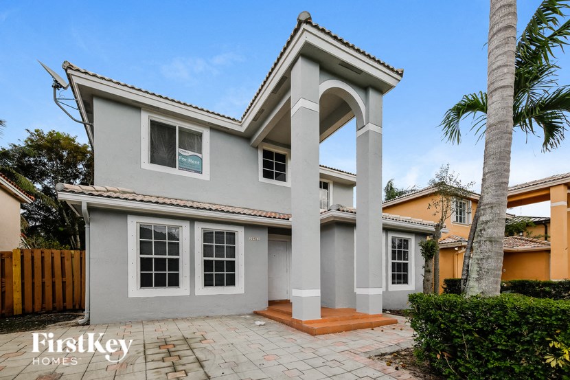 a white house with a porch and palm trees