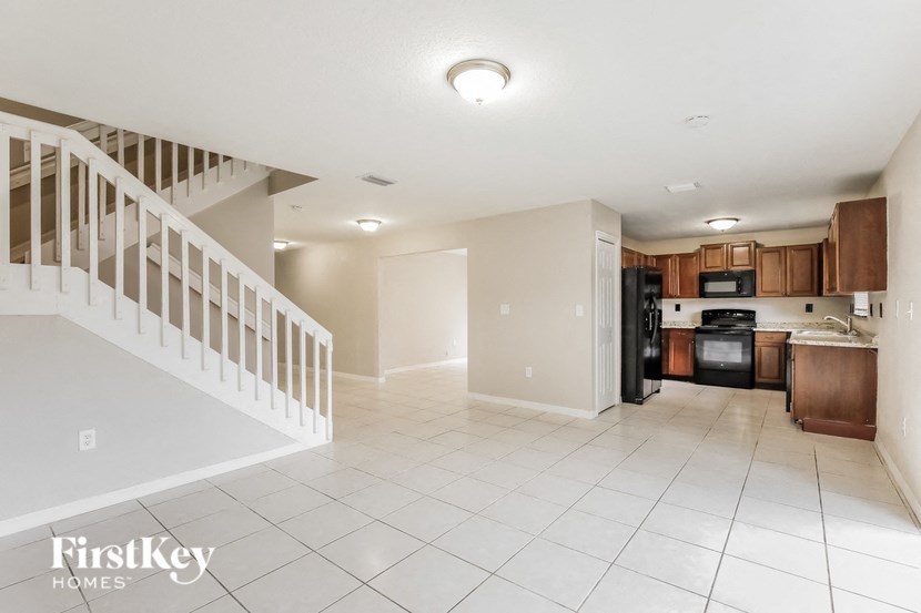 an empty living room with a staircase and a kitchen