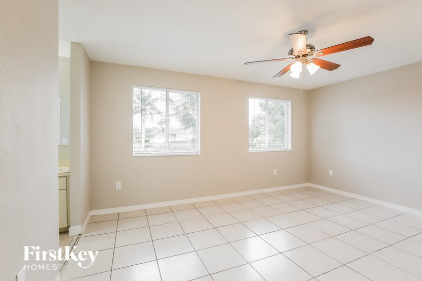 an empty living room with a ceiling fan and tiled floor