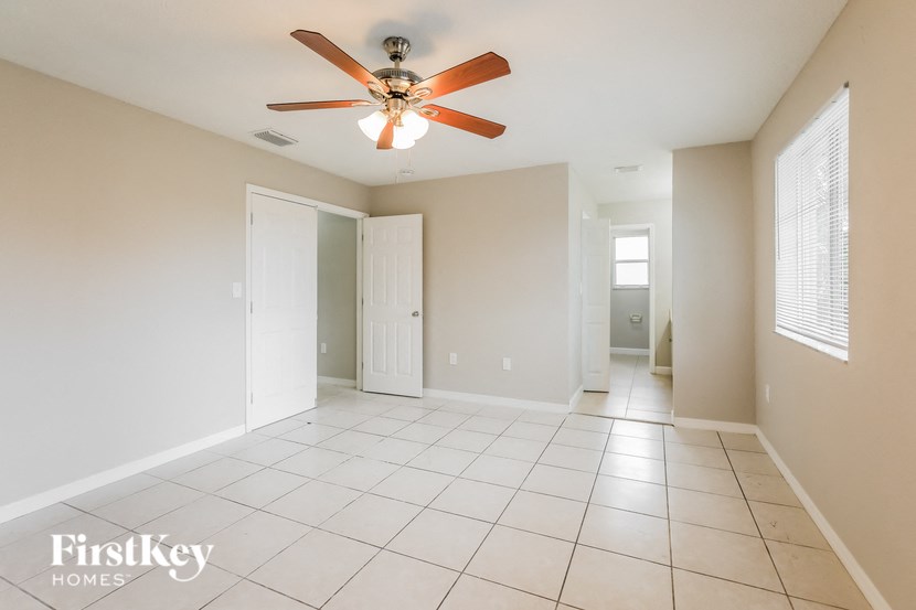 an empty living room with a ceiling fan and tiled floors
