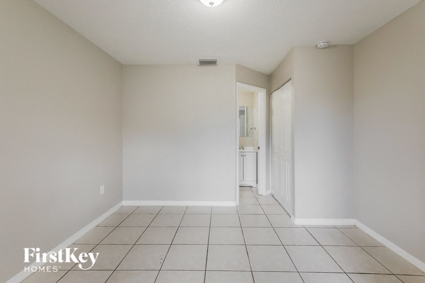an empty living room with tiled flooring and white walls