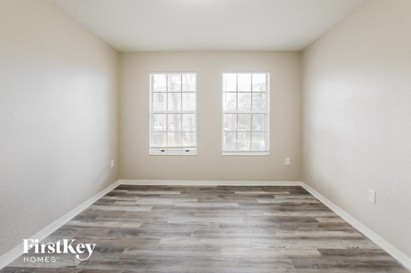 the living room of a new home with wood flooring and two windows