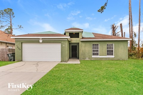 a green house with a driveway and a garage door