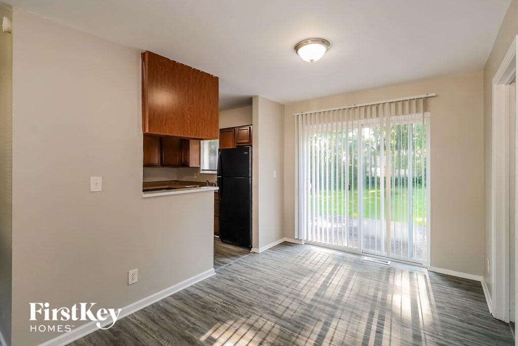 A room with a wooden cabinet and a black fridge.
