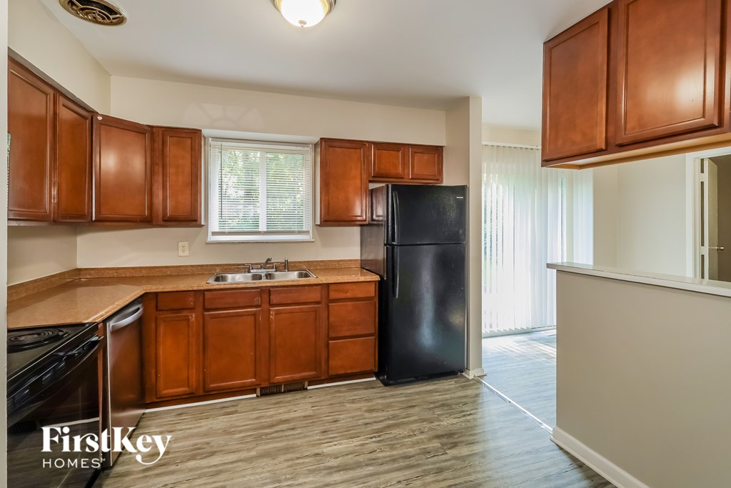 A kitchen with wooden cabinets and a black refrigerator.