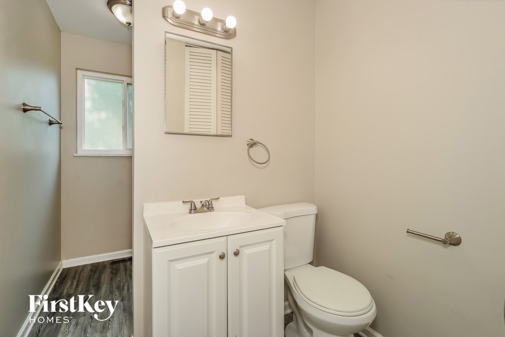 A white bathroom with a toilet, sink, and mirror.
